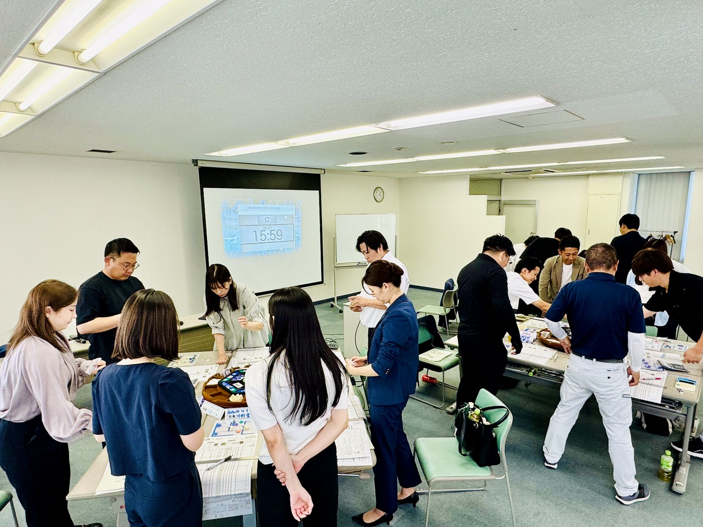 全員が立ち上がって卓を囲み、手を動かしている研修の風景