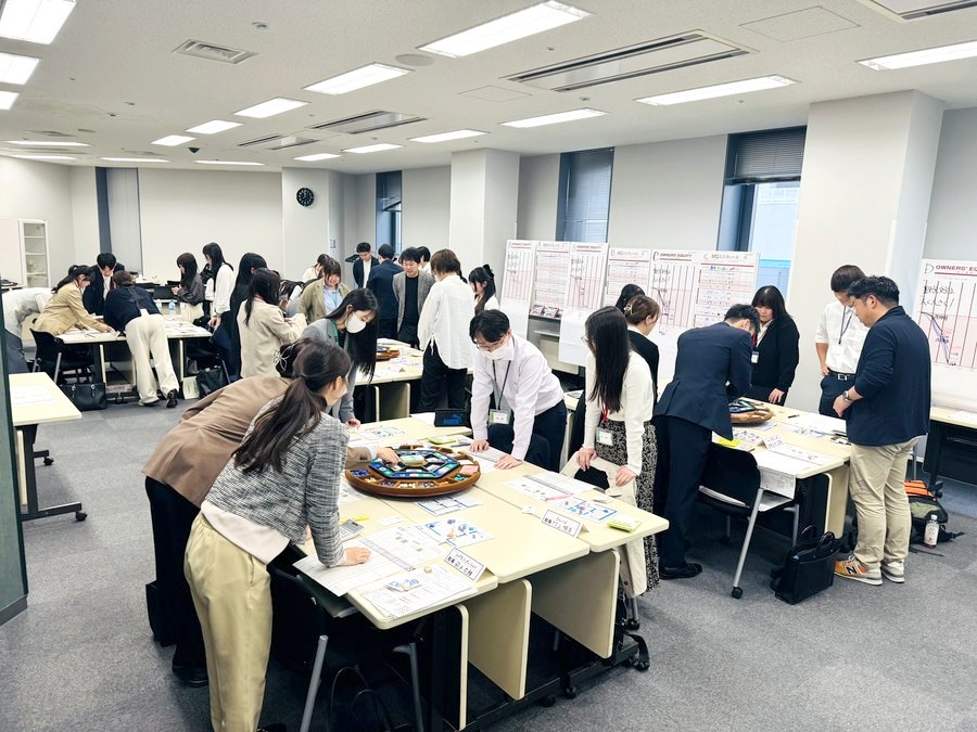 大勢が立ってゲーム盤を囲み経営を動かす